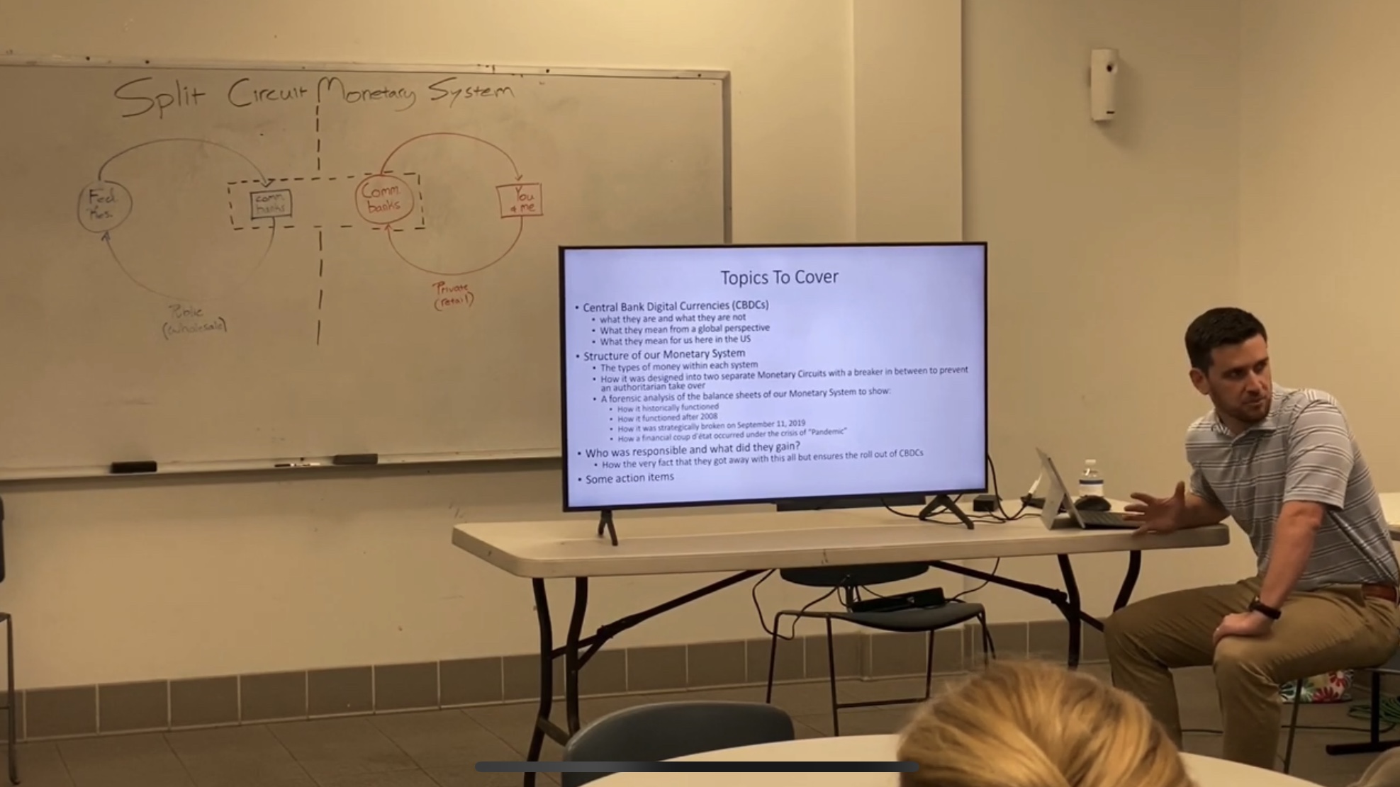 Drew presenting on central bank digital currencies beside a slide display and whiteboard